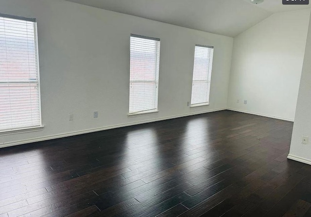 unfurnished room featuring vaulted ceiling, dark wood finished floors, and baseboards