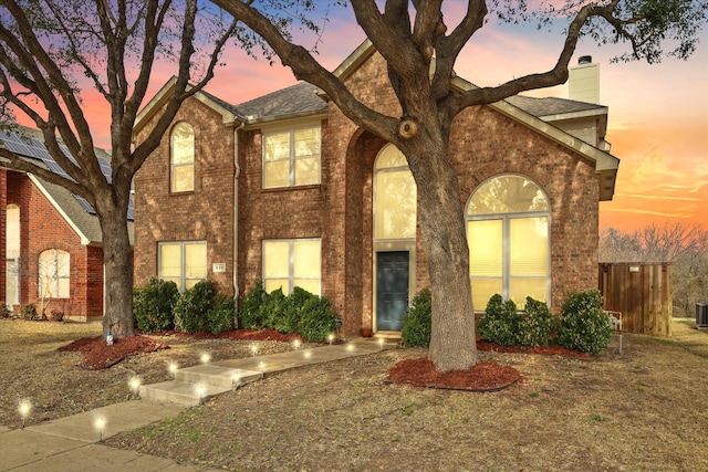 view of front of property with a chimney and brick siding