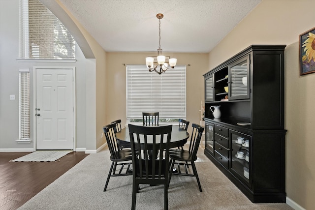 dining room featuring baseboards, a textured ceiling, arched walkways, and a notable chandelier