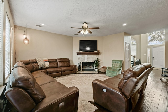 living area featuring dark wood-style floors, plenty of natural light, a tile fireplace, and visible vents