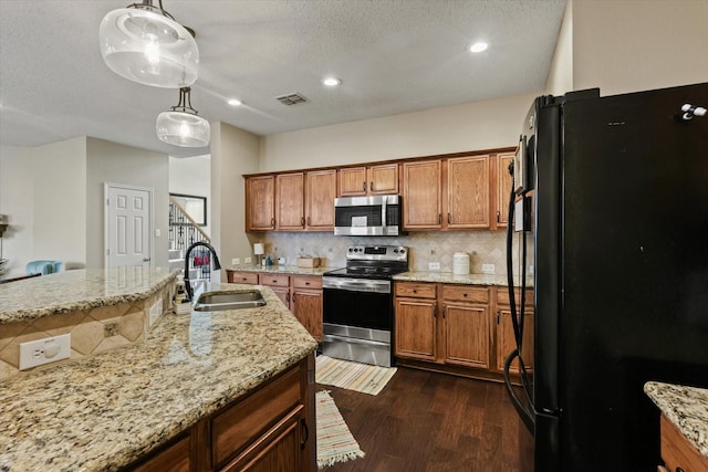 kitchen featuring dark wood-style floors, backsplash, appliances with stainless steel finishes, brown cabinetry, and a sink