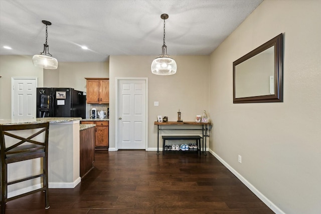 kitchen with pendant lighting, dark wood finished floors, freestanding refrigerator, and brown cabinets