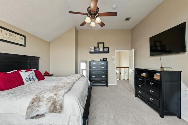 bedroom featuring visible vents, light carpet, vaulted ceiling, a textured ceiling, and ceiling fan