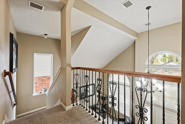 stairs with a textured ceiling, carpet, lofted ceiling, and visible vents