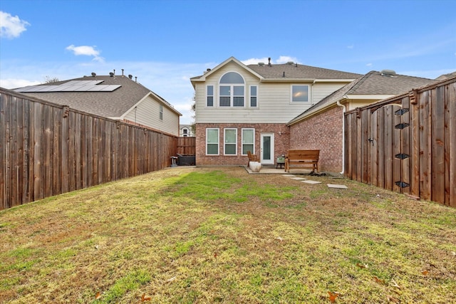 back of house with a yard, brick siding, and a fenced backyard