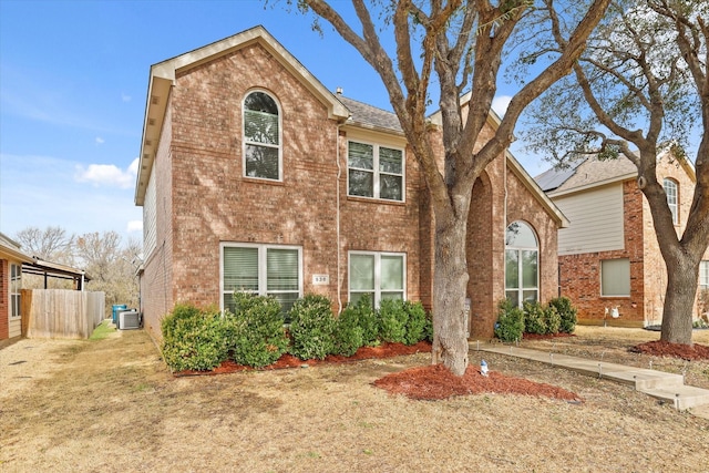 view of front of home featuring brick siding, fence, and central AC