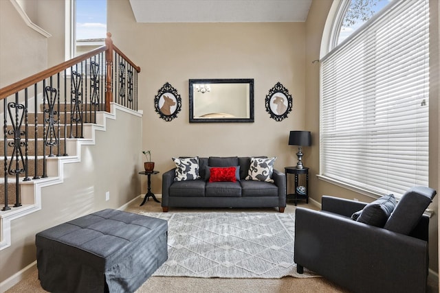 living room featuring baseboards, plenty of natural light, stairway, and carpet flooring