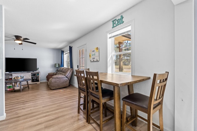 dining room with a ceiling fan, light wood-type flooring, and baseboards