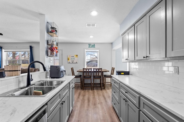 kitchen featuring visible vents, backsplash, a sink, and gray cabinetry