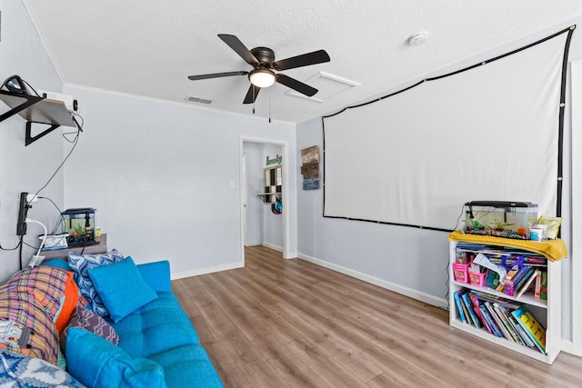 interior space featuring ornamental molding, ceiling fan, a textured ceiling, wood finished floors, and baseboards