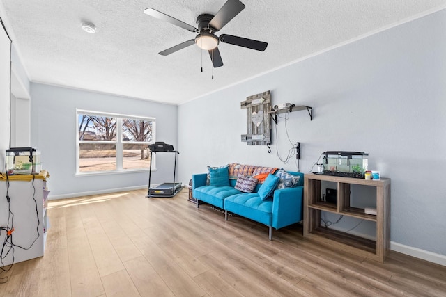 living area with a textured ceiling, ceiling fan, wood finished floors, and baseboards