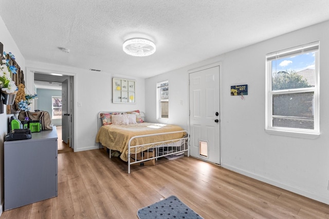 bedroom featuring light wood-style floors, baseboards, and a textured ceiling