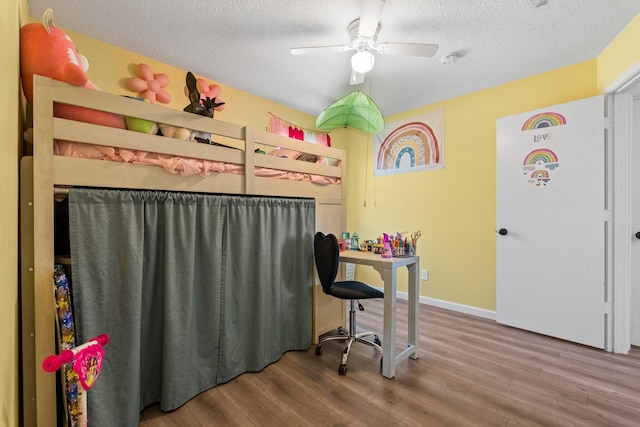 bedroom featuring a textured ceiling, baseboards, and wood finished floors