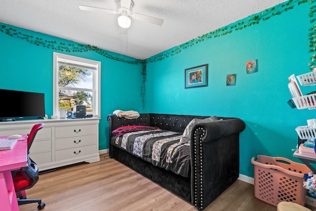 bedroom featuring ceiling fan, a textured ceiling, baseboards, and wood finished floors