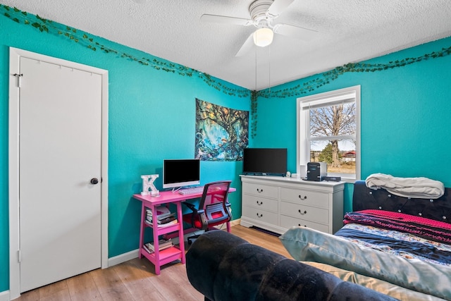 bedroom with a textured ceiling, light wood-type flooring, a ceiling fan, and baseboards