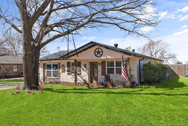 view of front of home with brick siding, a front yard, and fence