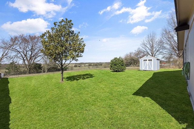 view of yard featuring a storage shed, fence, and an outdoor structure