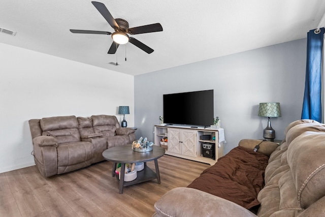 living area with ceiling fan, wood finished floors, and visible vents