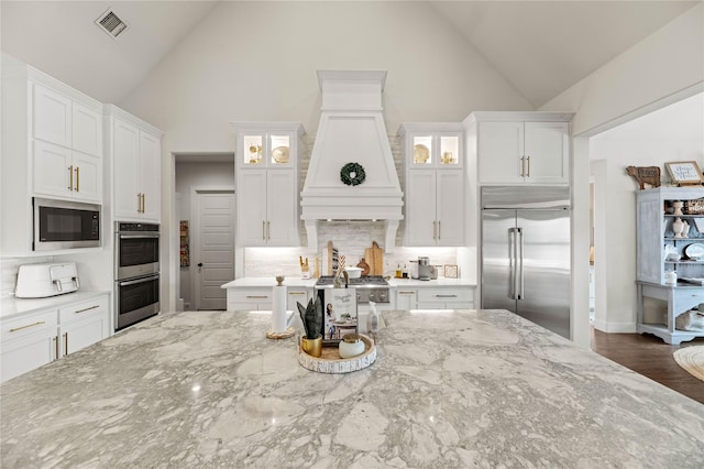 kitchen featuring white cabinetry, glass insert cabinets, and built in appliances