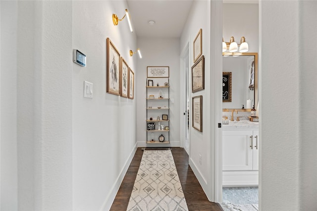 corridor featuring a sink, baseboards, and dark wood-style floors