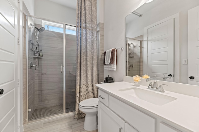 bathroom with vanity, a shower stall, and toilet