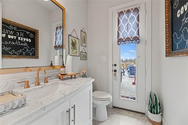 bathroom with toilet, vanity, and baseboards