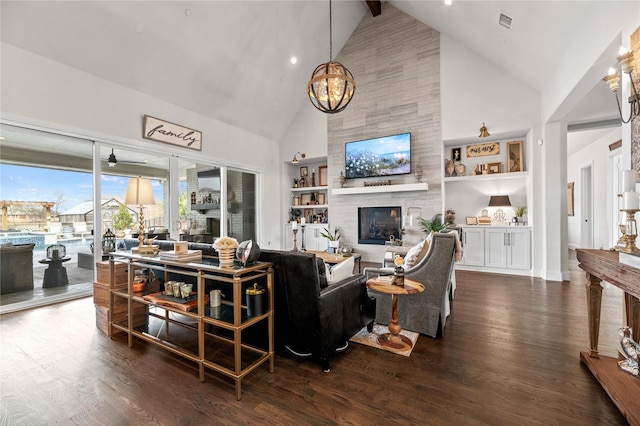 living area with built in shelves, an inviting chandelier, dark wood-style floors, and a tile fireplace