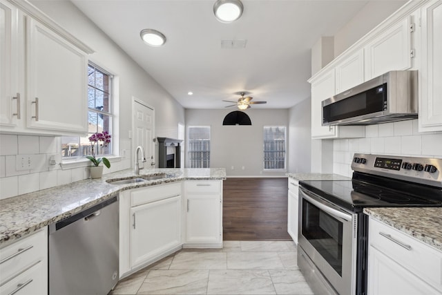 1153 Regal Dr, Garland, TX 75040 - kitchen with stainless steel appliances, a sink, healthy amount of natural light, a peninsula, and recessed lighting