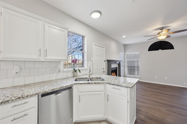 1153 Regal Dr, Garland, TX 75040 - kitchen featuring stainless steel dishwasher, a sink, a peninsula, white cabinetry, and backsplash