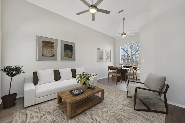 living room with lofted ceiling, ceiling fan, wood finished floors, visible vents, and baseboards