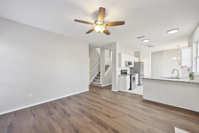 1153 Regal Dr, Garland, TX 75040 - kitchen featuring appliances with stainless steel finishes, a sink, wood finished floors, white cabinets, and a ceiling fan