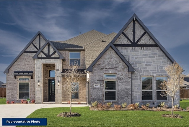 view of front facade with a shingled roof, a front lawn, and brick siding