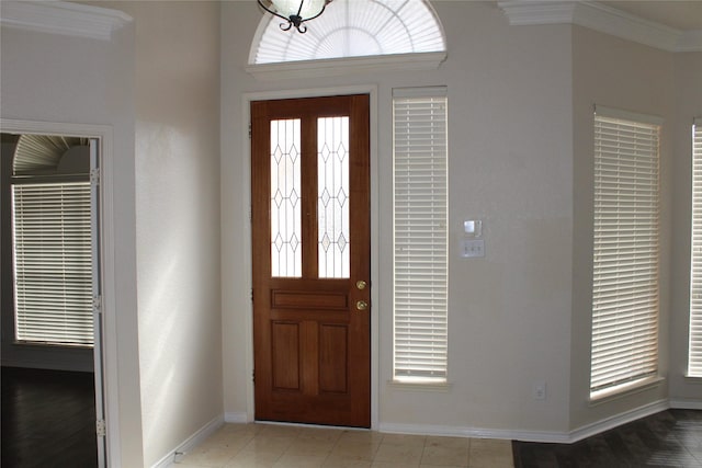 foyer featuring crown molding and baseboards