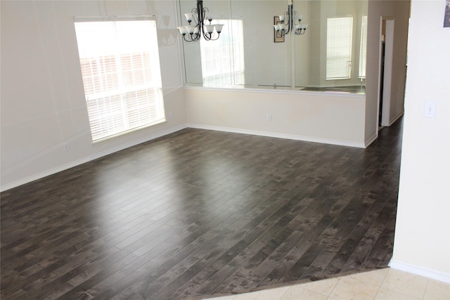 unfurnished dining area with wood finished floors, baseboards, and a chandelier