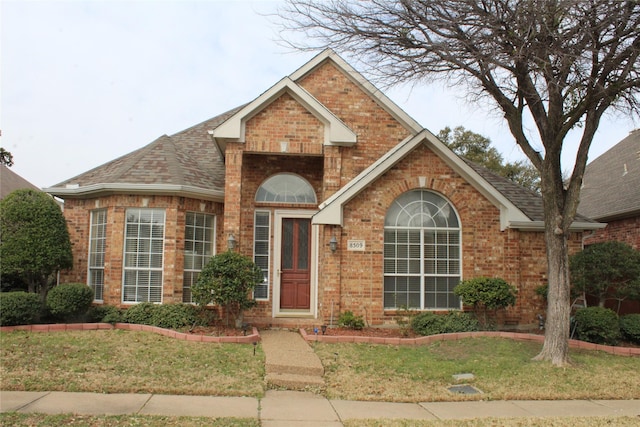 8509 Mustang Dr, Irving, TX 75063 - traditional-style house featuring brick siding, a front lawn, and roof with shingles