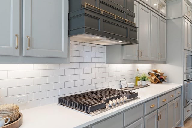 kitchen featuring light countertops, backsplash, appliances with stainless steel finishes, and custom exhaust hood