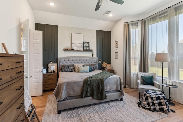 bedroom with multiple windows, vaulted ceiling, light wood-style flooring, and visible vents