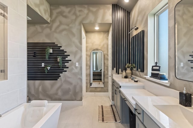 full bathroom featuring tile patterned flooring, double vanity, a sink, and a freestanding bath