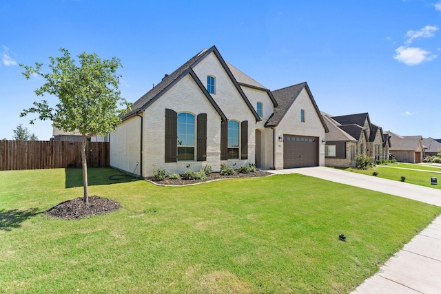 french country inspired facade with brick siding, concrete driveway, an attached garage, fence, and a front lawn