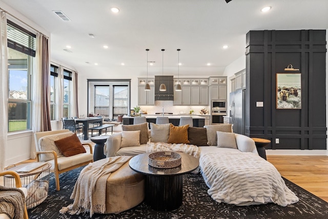 living room featuring recessed lighting, visible vents, and light wood finished floors