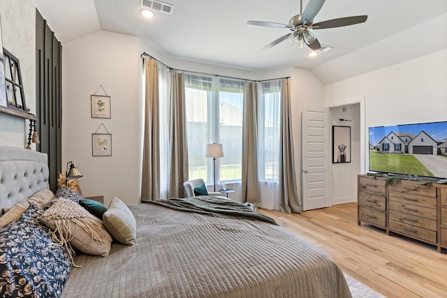 bedroom with a ceiling fan, visible vents, vaulted ceiling, and light wood-style flooring