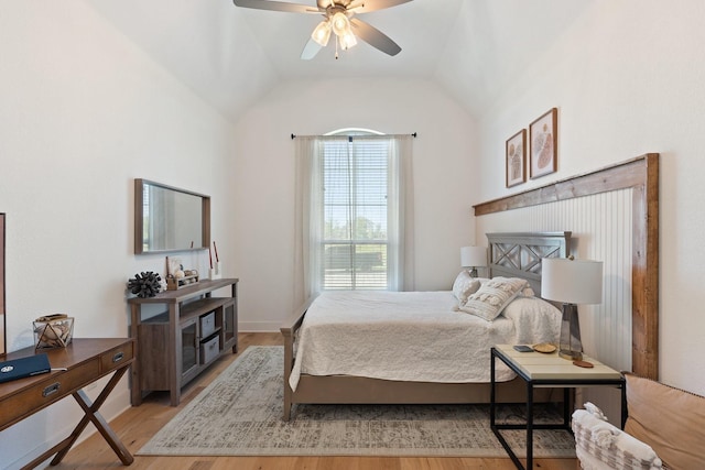 bedroom with a ceiling fan, light wood-style flooring, lofted ceiling, and a fireplace