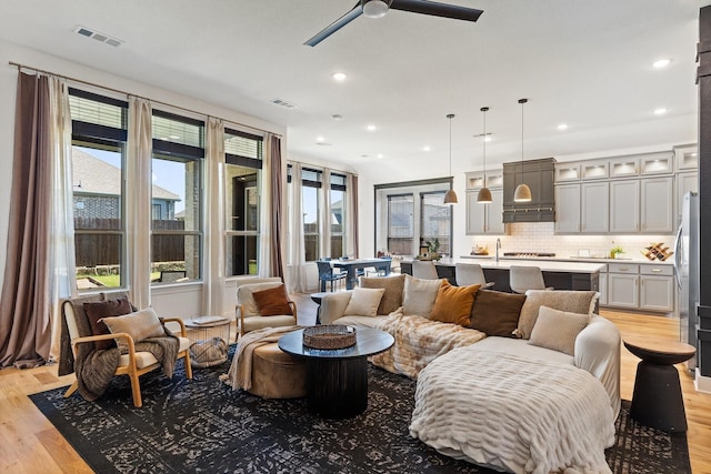 living area featuring recessed lighting, a ceiling fan, light wood-type flooring, and visible vents