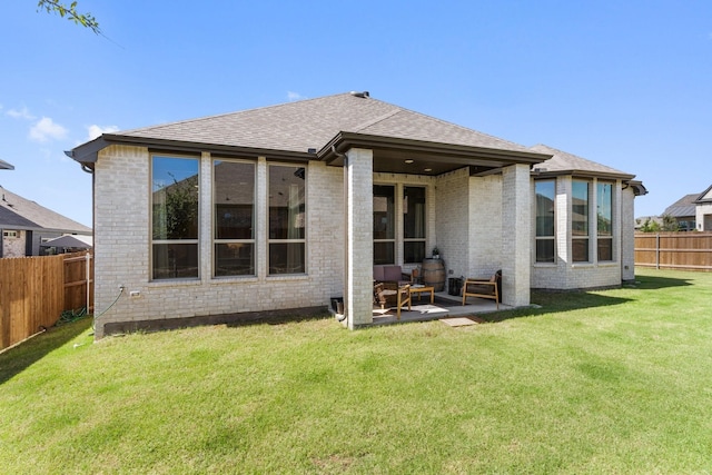 back of house featuring a fenced backyard, brick siding, and a lawn