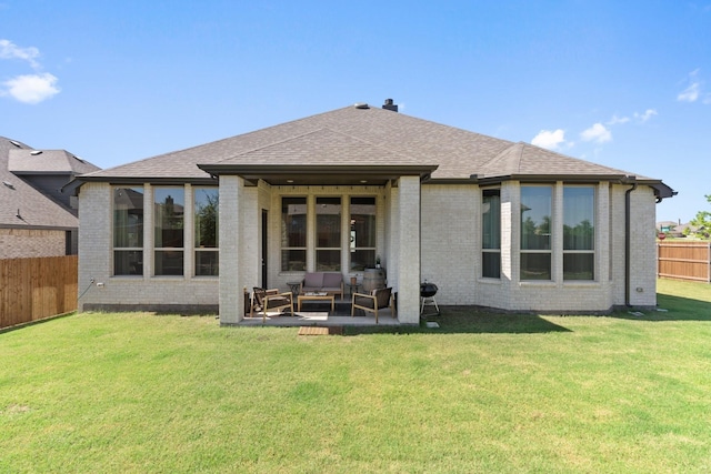 back of house with brick siding, roof with shingles, a lawn, a patio area, and a fenced backyard