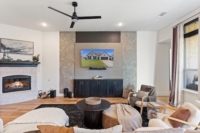 living room featuring a ceiling fan, visible vents, a fireplace, wood finished floors, and recessed lighting