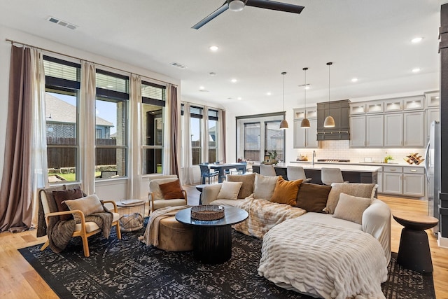 living room featuring light wood finished floors, visible vents, and recessed lighting