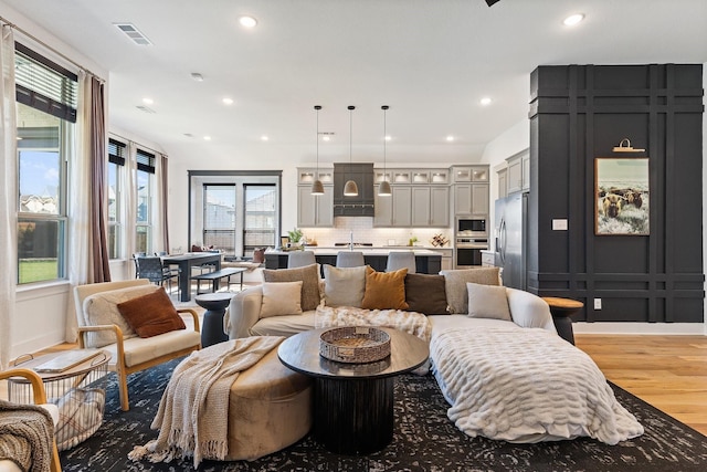 living room with recessed lighting, visible vents, and light wood finished floors