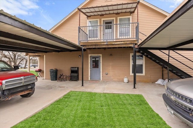 back of house featuring a lawn, a balcony, and a patio