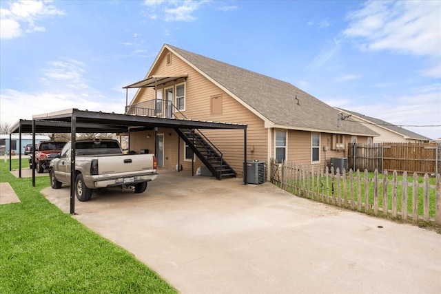 view of home's exterior featuring an attached carport, central air condition unit, fence, stairs, and a yard